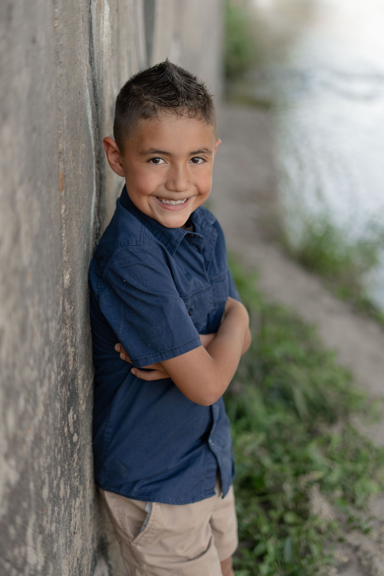 Casual outdoor photos of a child in navy blue shirt and khaki shorts against a wall.