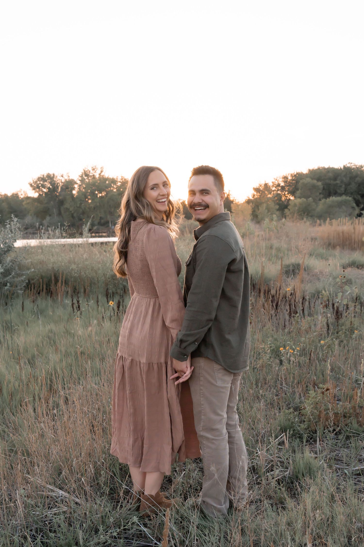 Couple embracing during romantic outdoor photoshoot at sunset.