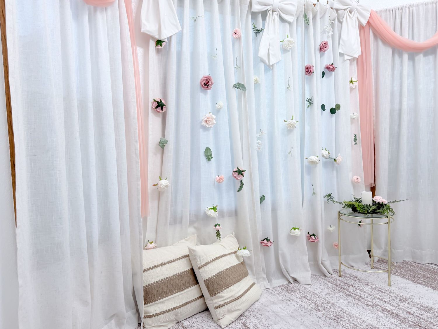 A cozy corner with white curtains, decorative butterflies and flowers, and striped pillows against a dreamy backdrop.