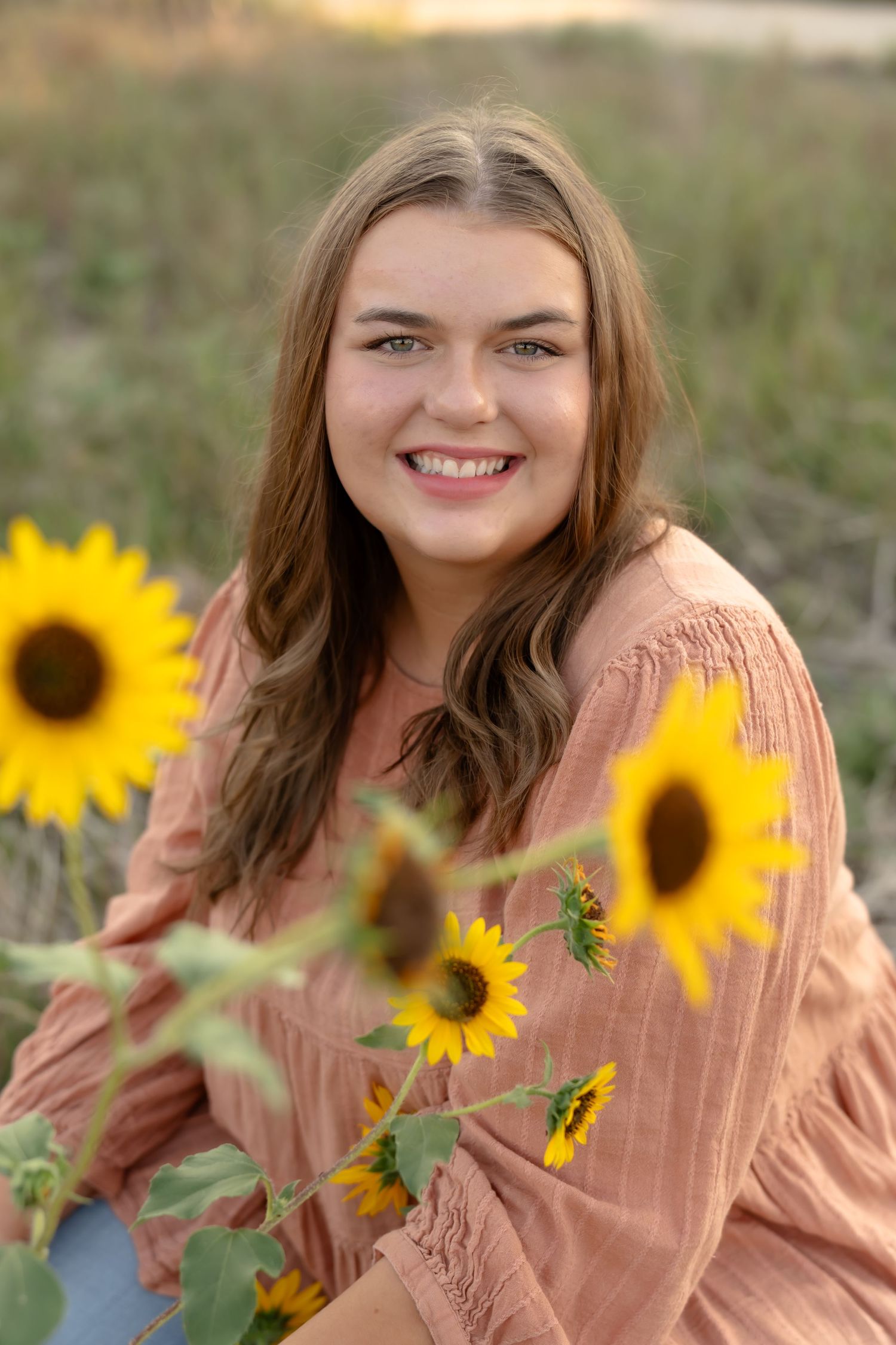 Portrait session in peachy tones with bright sunflowers in natural outdoor setting.