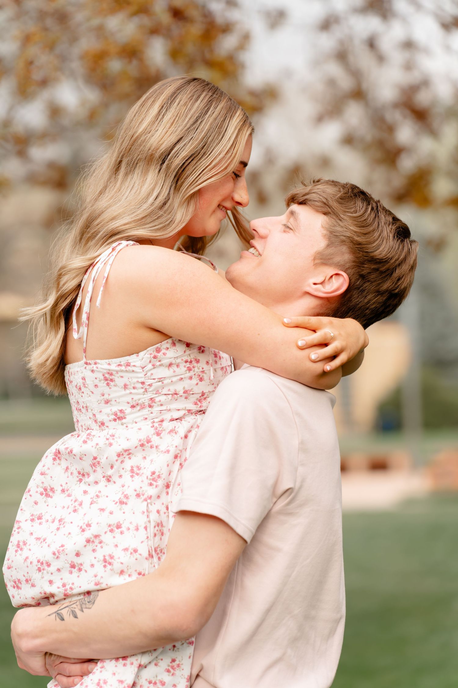 A romantic couple embracing in a park during a warm summer day.
