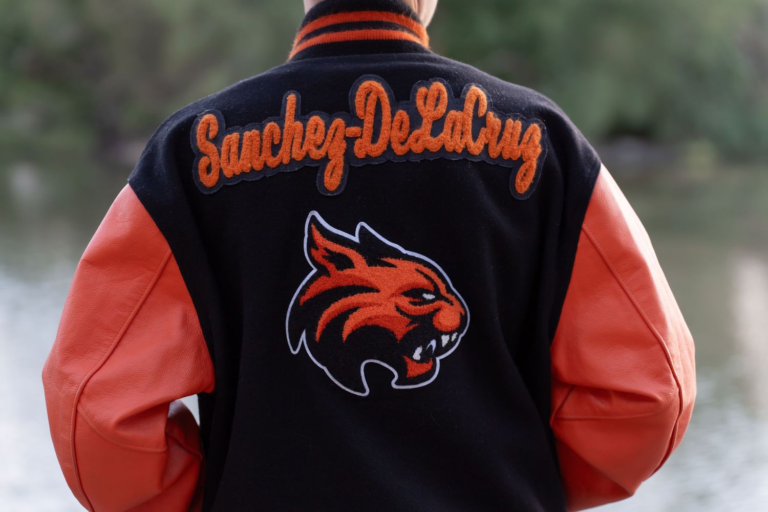 Black and orange varsity jacket with Sanchez-DeLaPaz text and wildcat mascot logo.