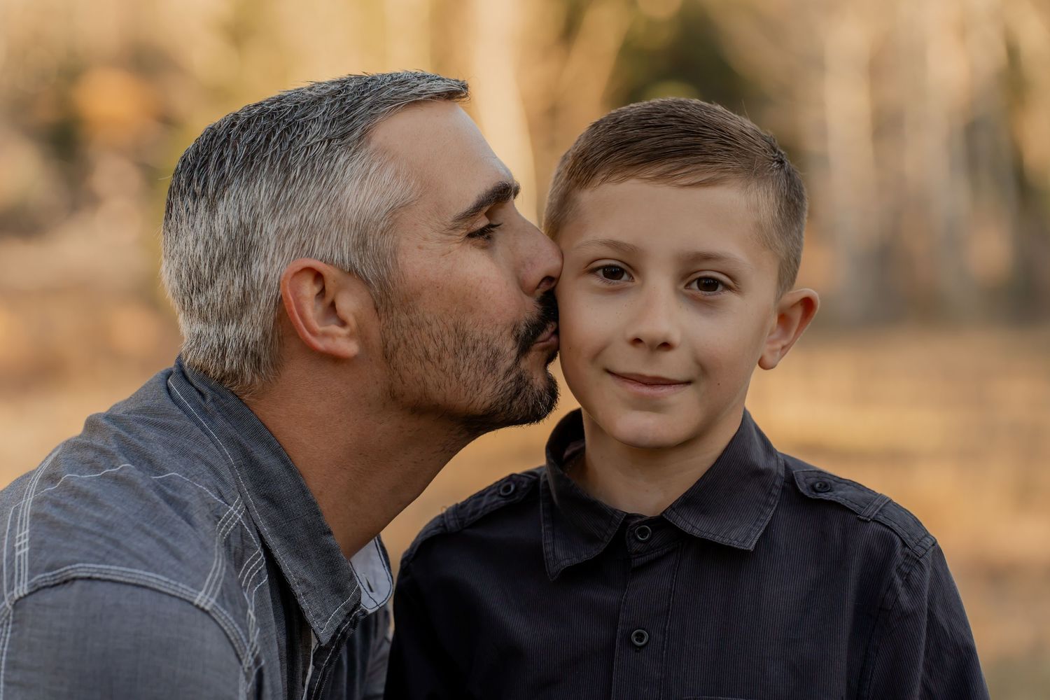 A father and son share tender moments outdoors during golden hour in a series of connected photos.