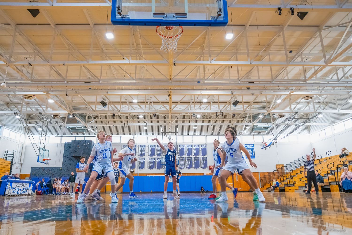 Wide angle view of a high school gymnasium during a basketball game.