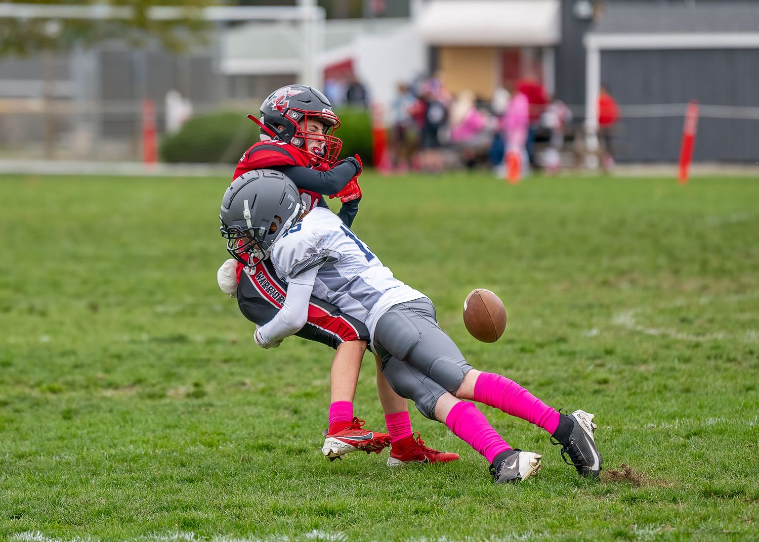 Football player diving for loose ball during outdoor game on grass field.