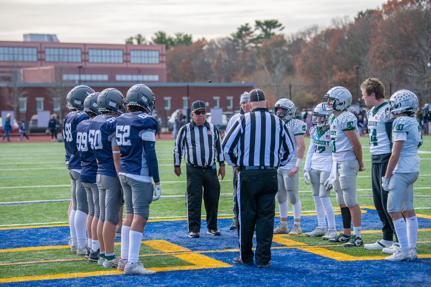 Football teams and officials line up on opposite sides of the field during pre-game.