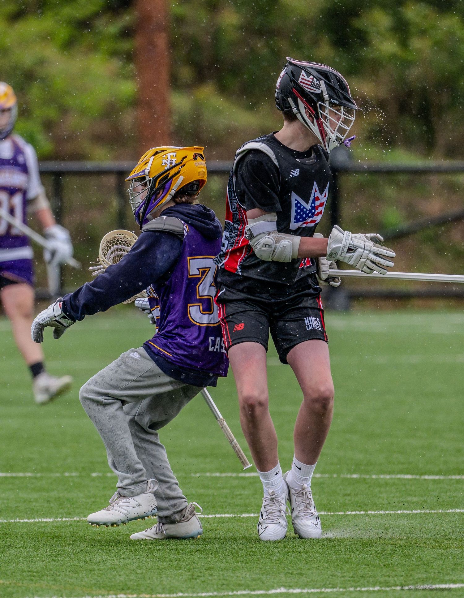 Lacrosse players in purple and black uniforms practicing face-off positions.
