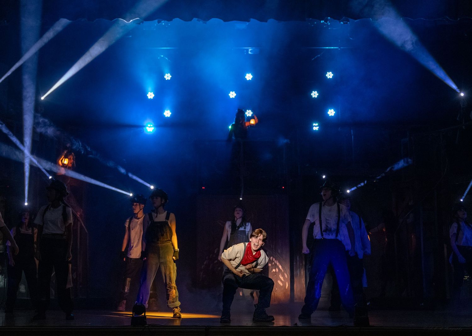 Stage performance with dramatic blue lighting and silhouetted figures.