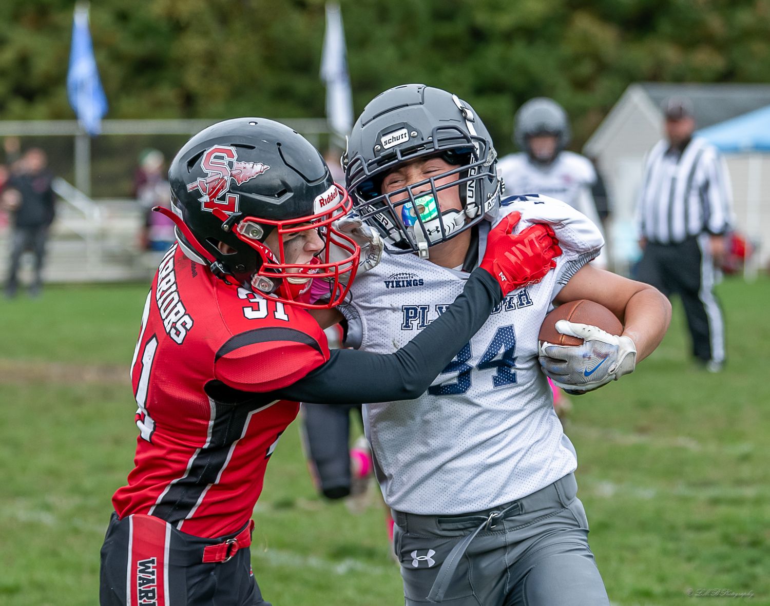 Football players in red and gray uniforms battling for possession during competitive play.