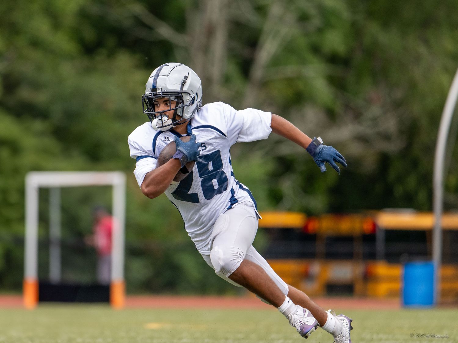 A football player in white uniform runs with the ball during a game.