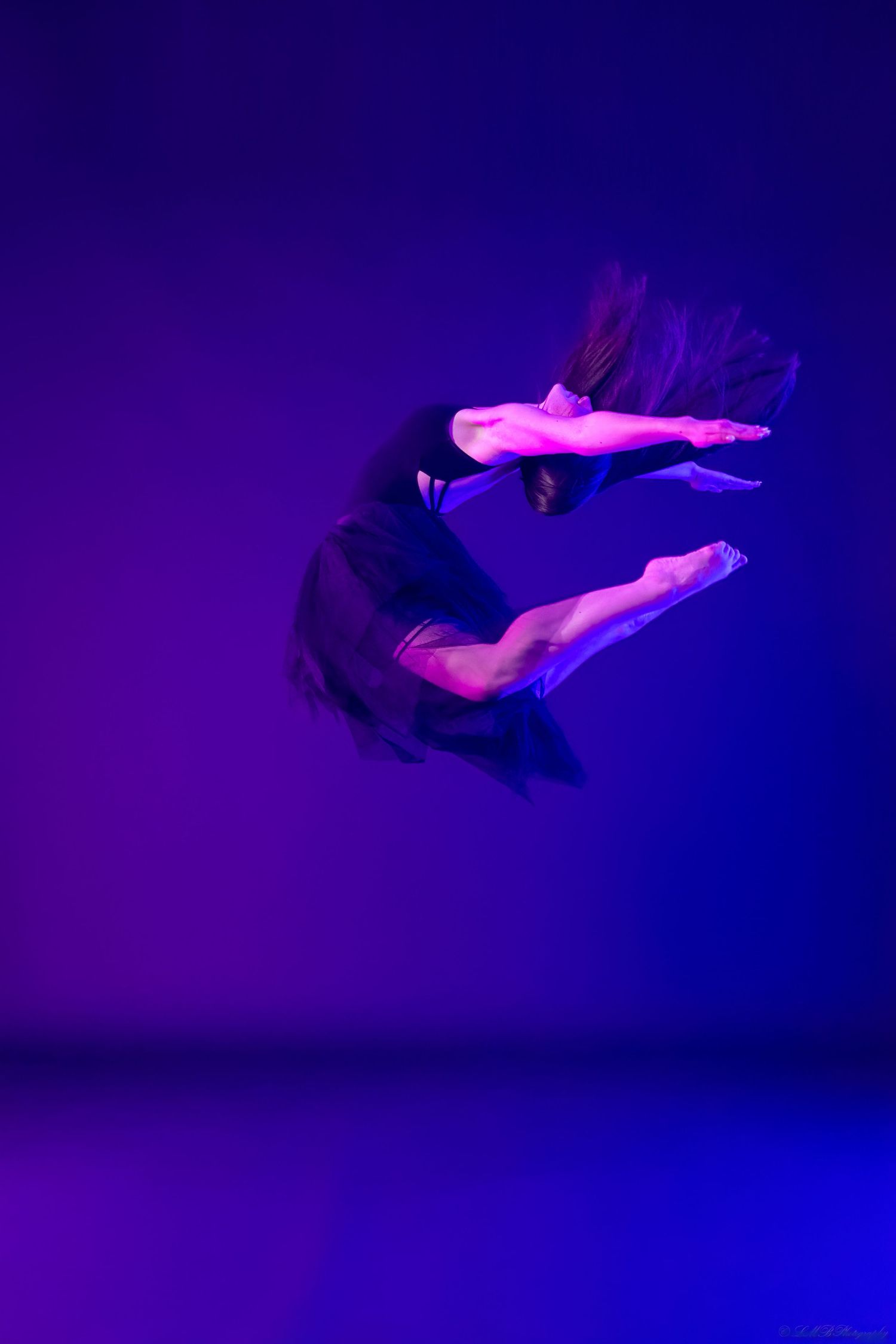 Athletic dance movements photographed against deep purple lighting creating dramatic silhouettes.