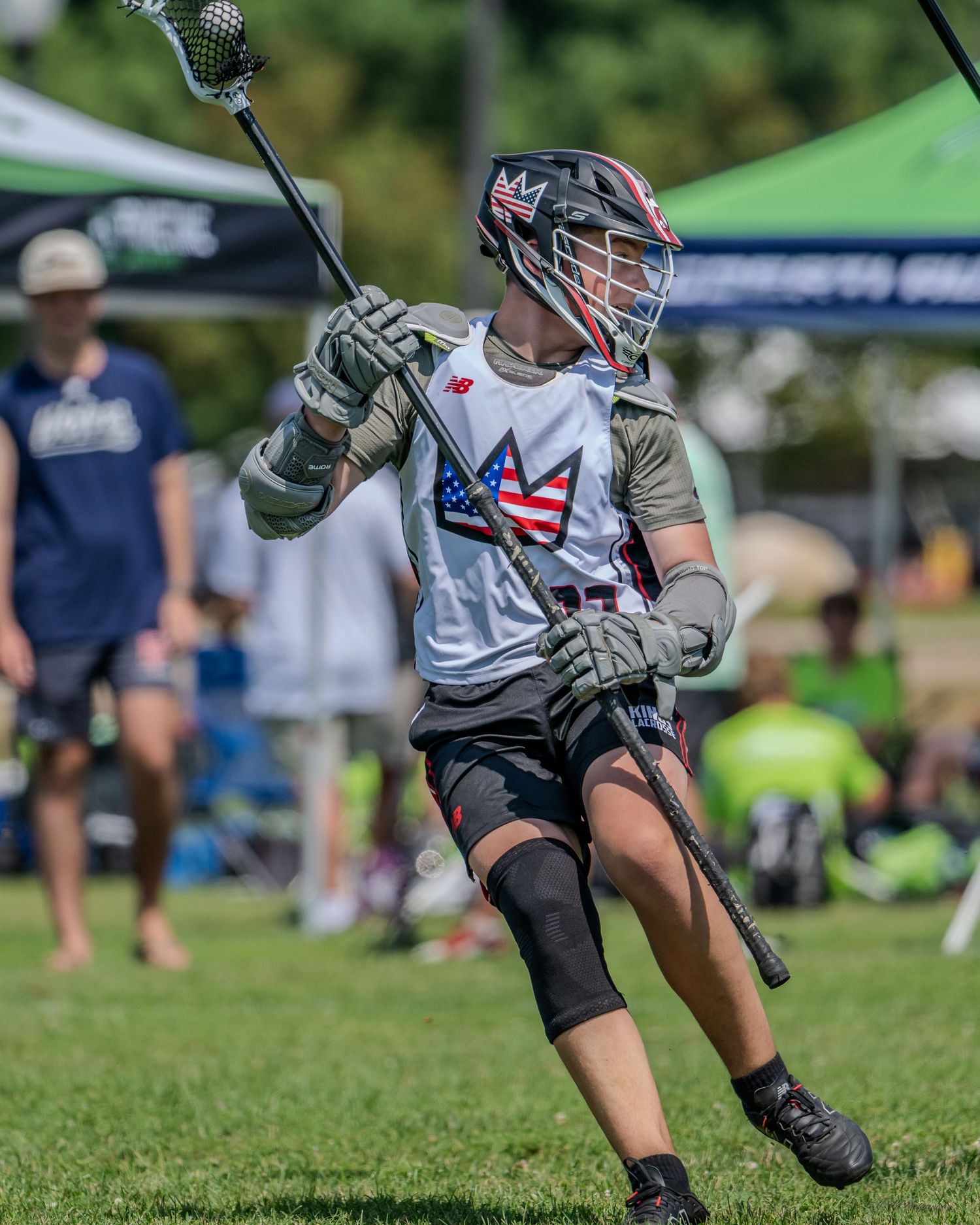 Players with lacrosse sticks competing for ball possession on grass field.