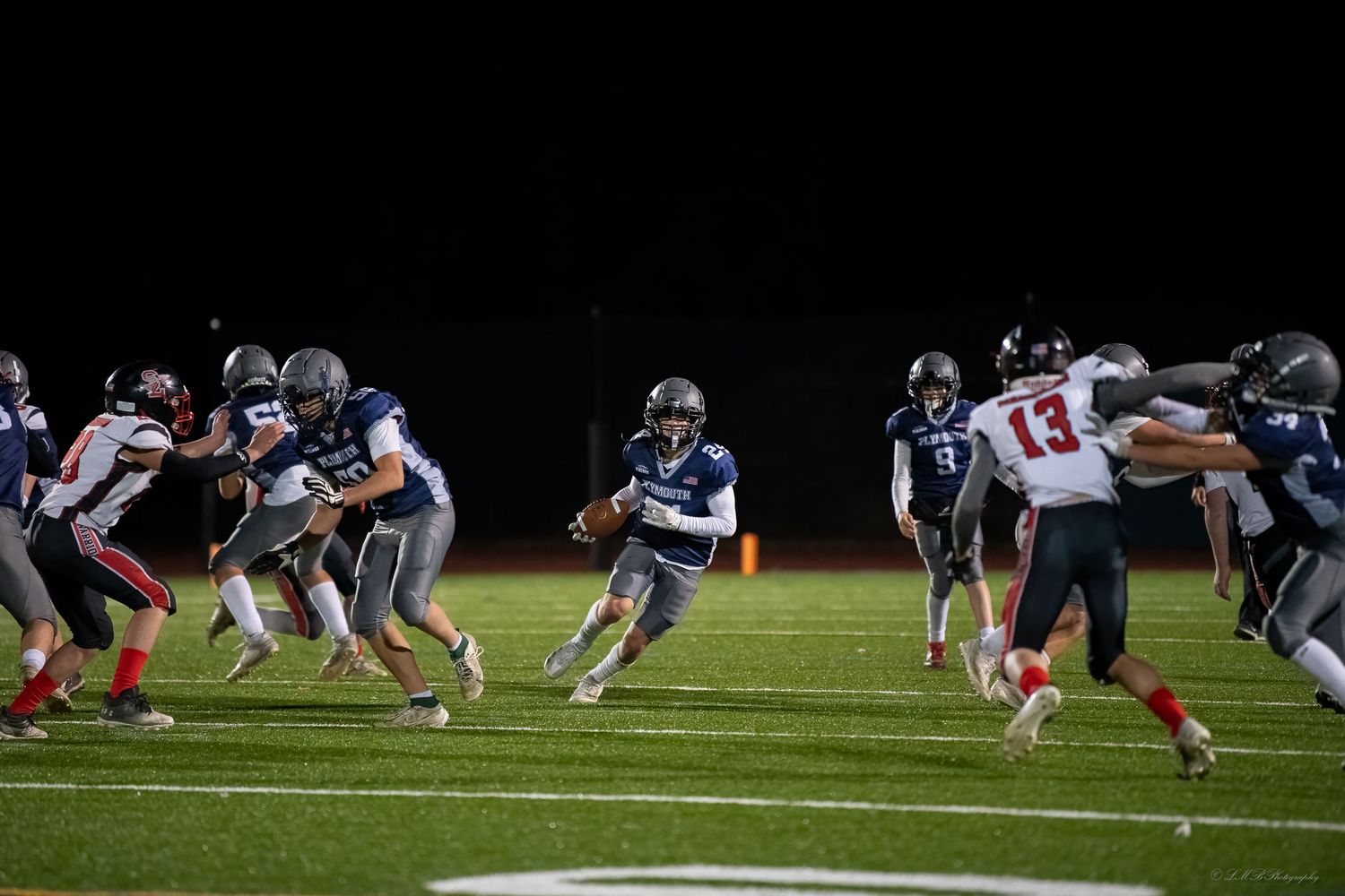 Football teams line up at the line of scrimmage during a night game.
