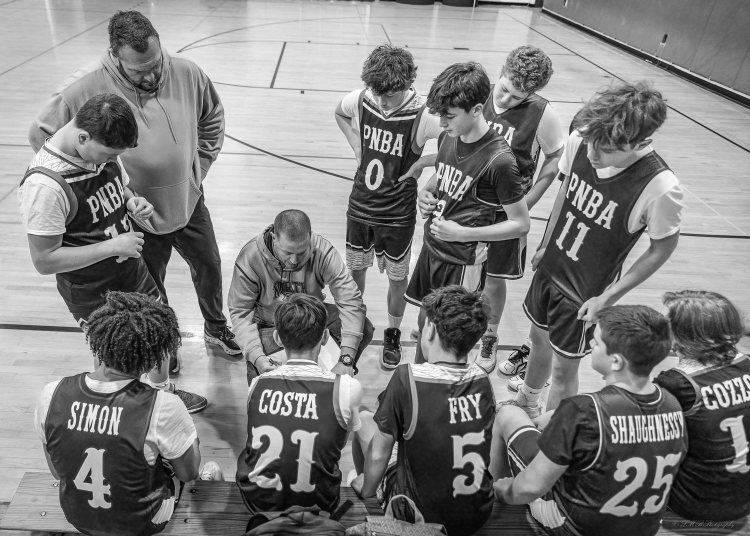 Youth sports team huddled together in black jerseys during pre-game strategy discussion.