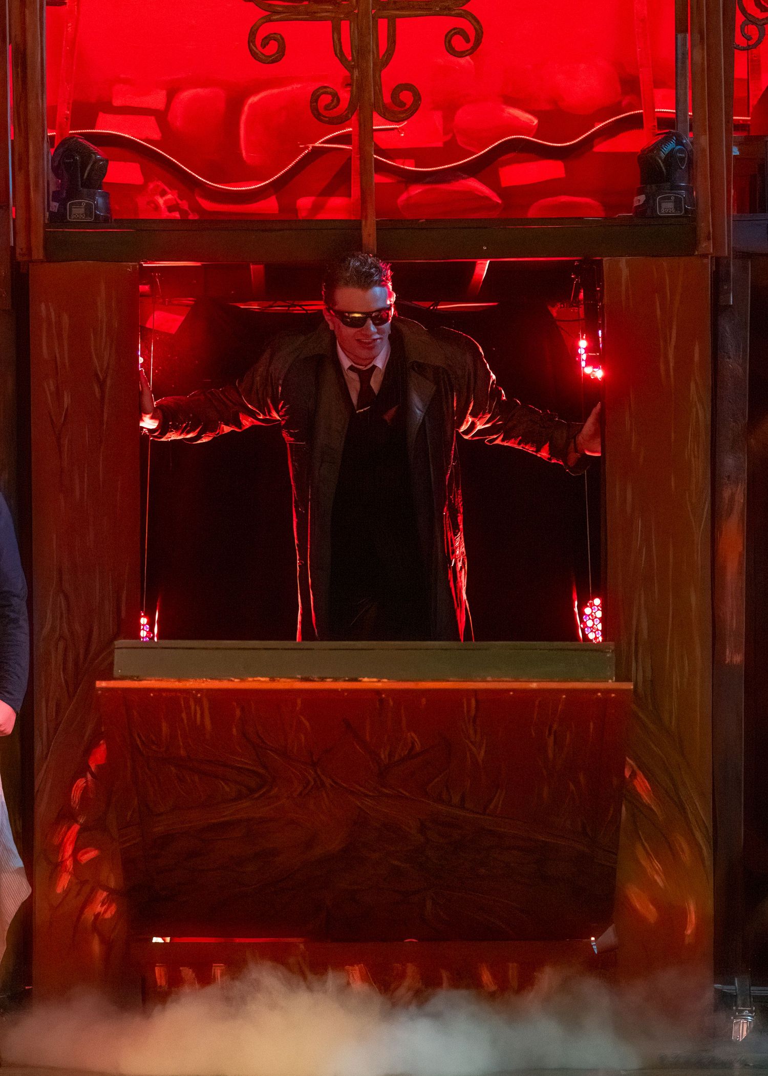 Red-lit theatrical set with ornate wooden fixtures and atmospheric fog effects.