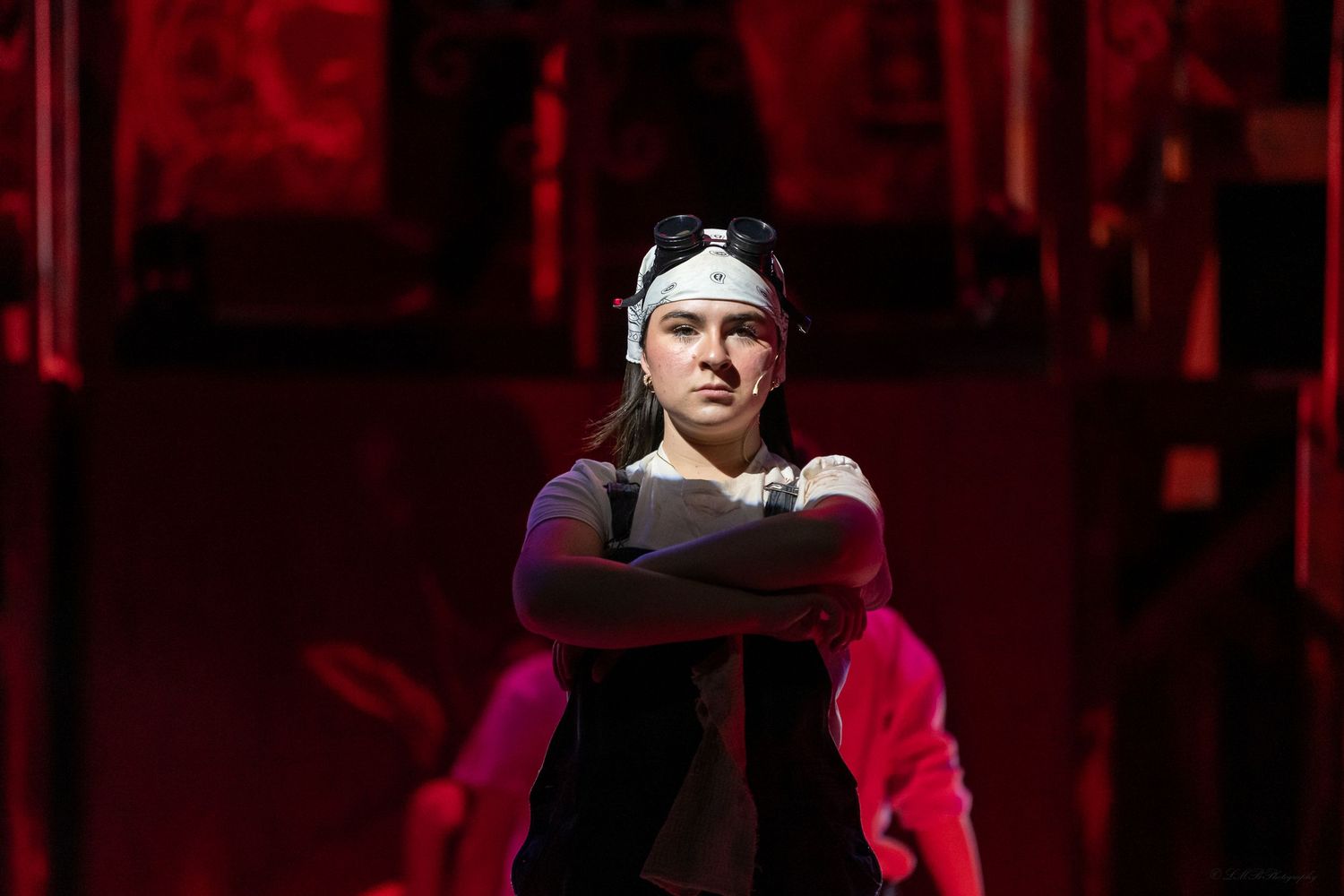 Stage performance with dramatic red lighting and performers in dark costumes.