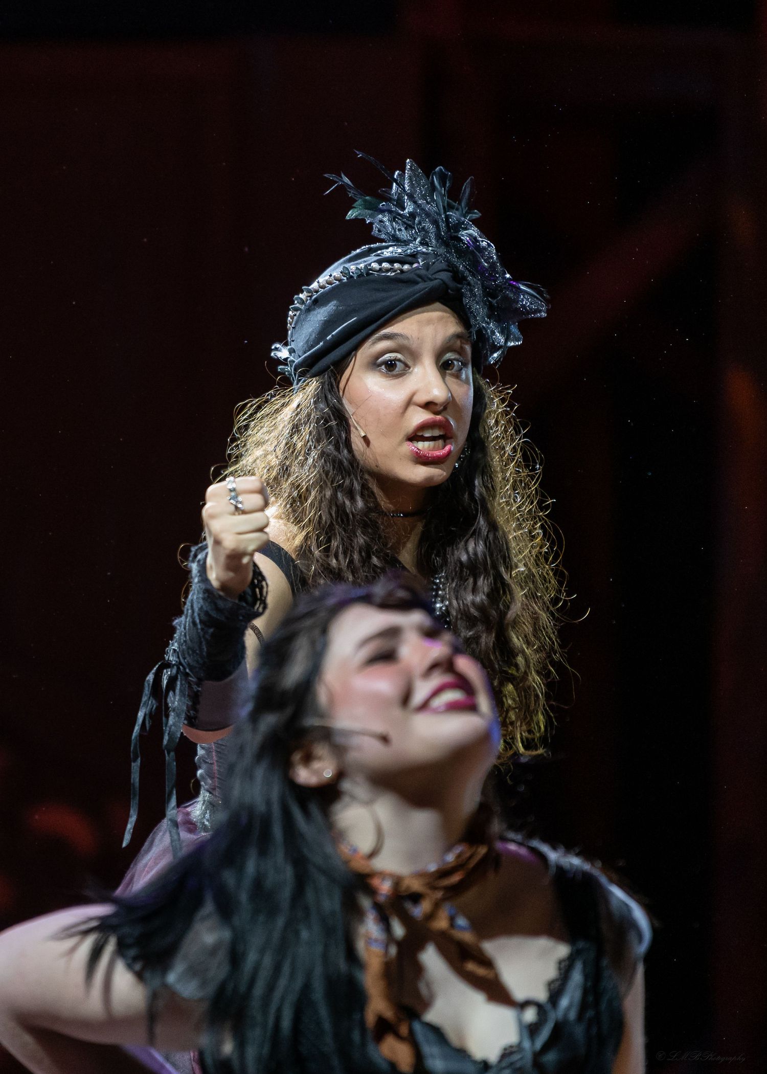 Theatrical performance with dramatic lighting and performers in period costumes.