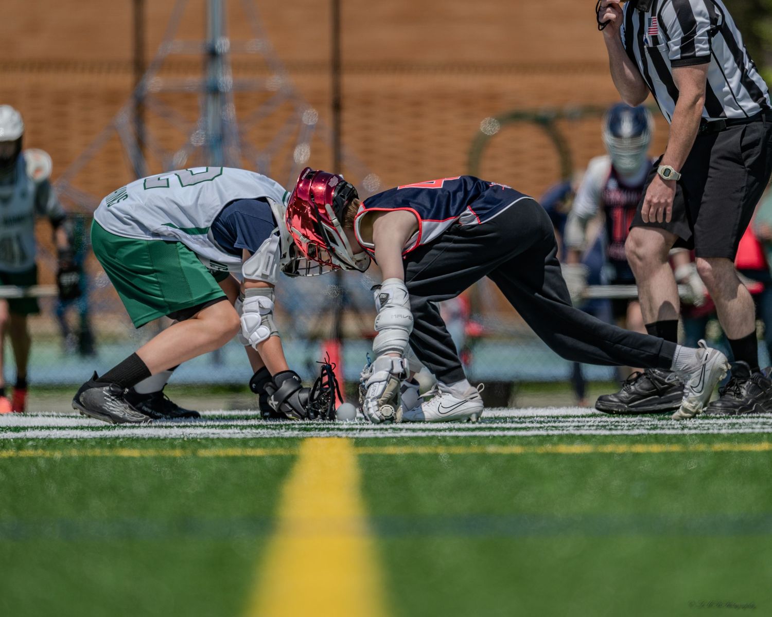 Close-up view of lacrosse players' feet and cleats on grass field during face-off position.
