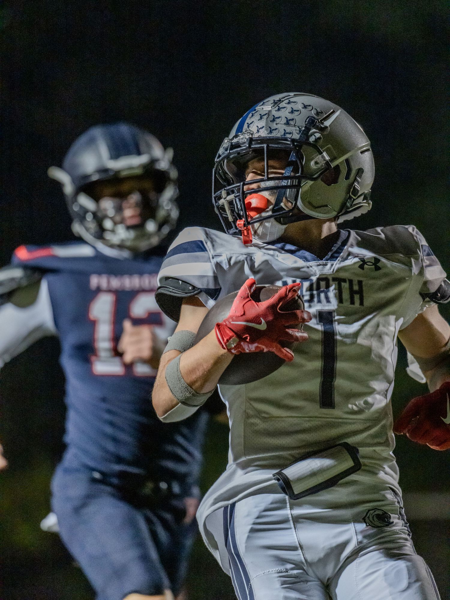 Football players from opposing teams in action during an intense nighttime match.