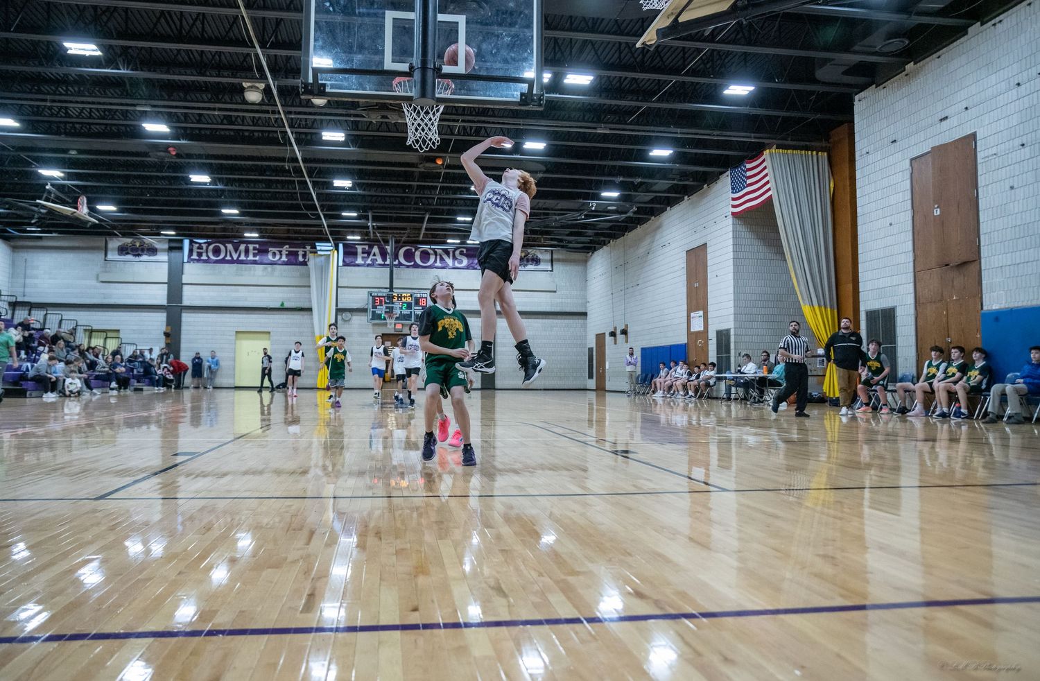 Panoramic view of an indoor basketball court with players practicing.
