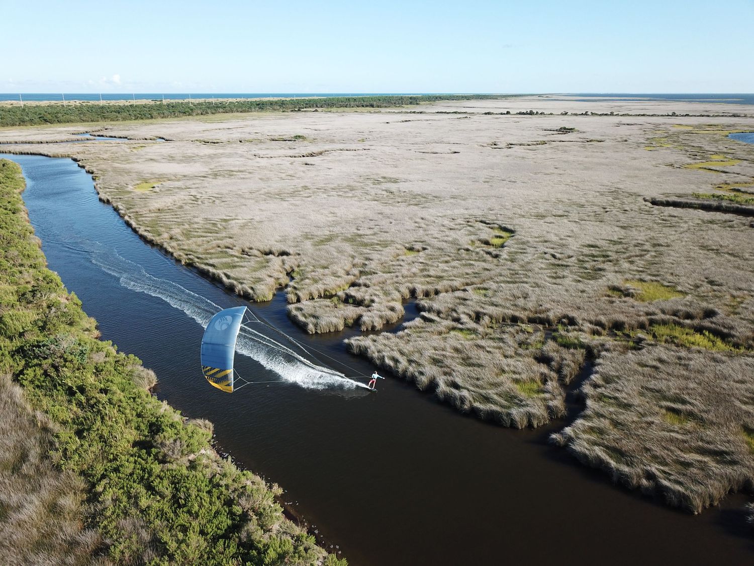 Aerial panorama of kitesurfer in winding river through coastal wetlands and marshes,Cape Hatteras