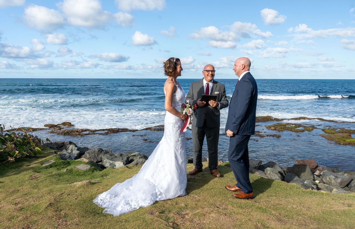 A coastal wedding ceremony with guests gathered on a scenic oceanfront cliff under blue skies. Wedding Photography in Puerto Rico