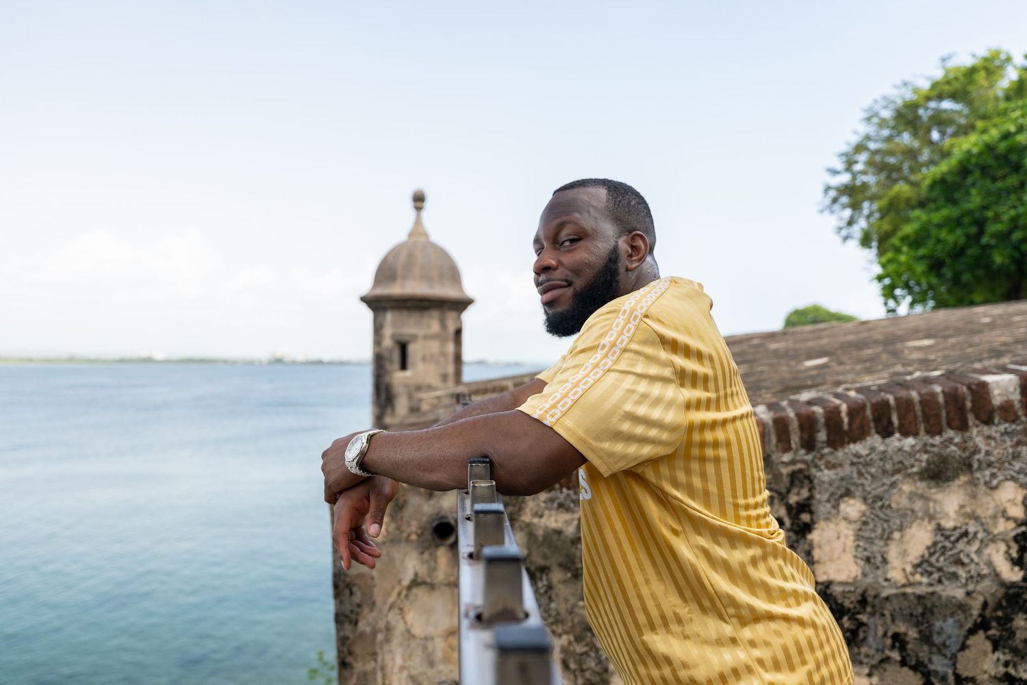Person in yellow sweater exploring historic stone fortress walls by the ocean.