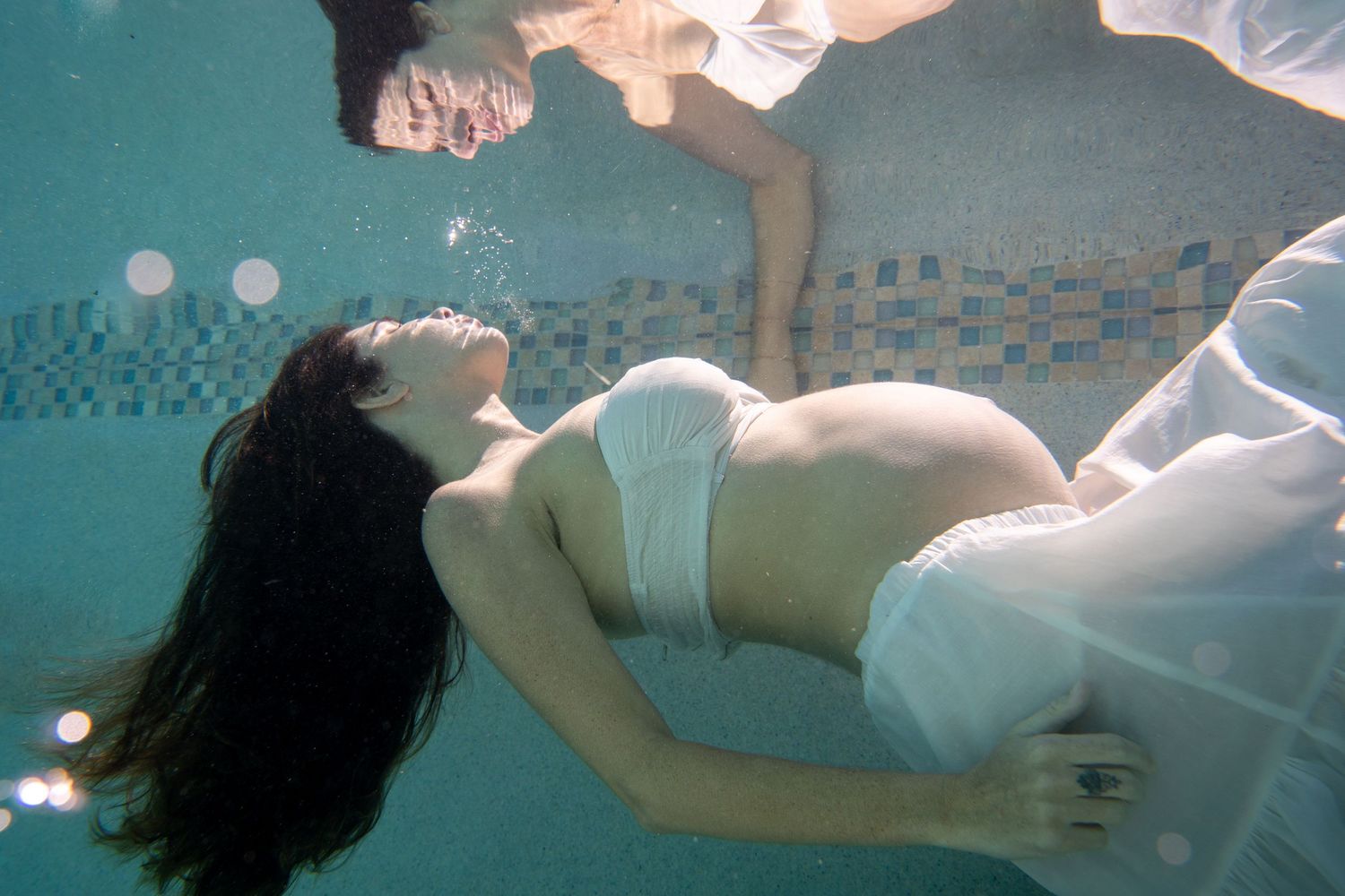 Underwater maternity photography sequence showing a figure floating in turquoise water.