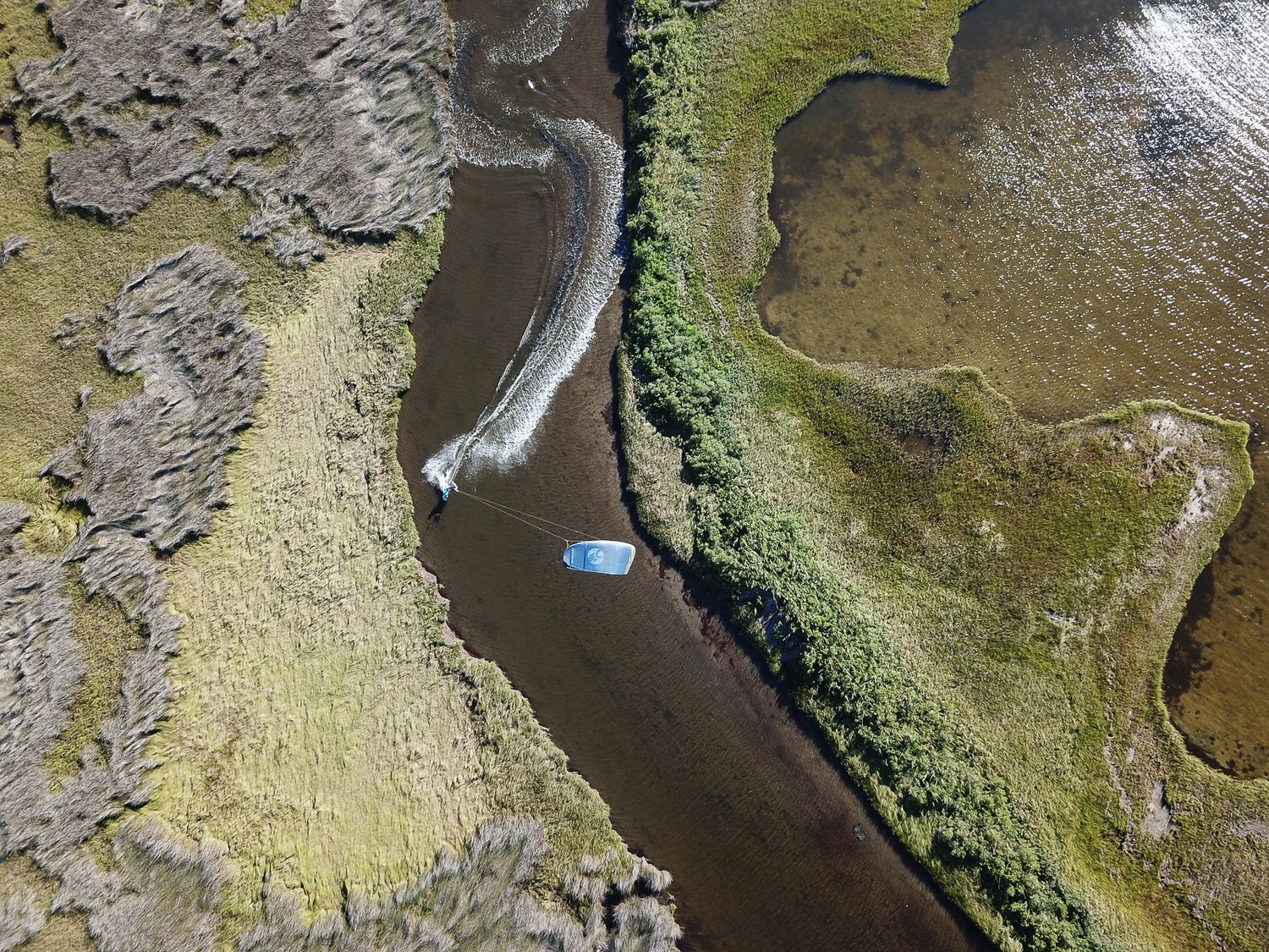 Aerial view of a kayak navigating through a winding river channel in marshland.