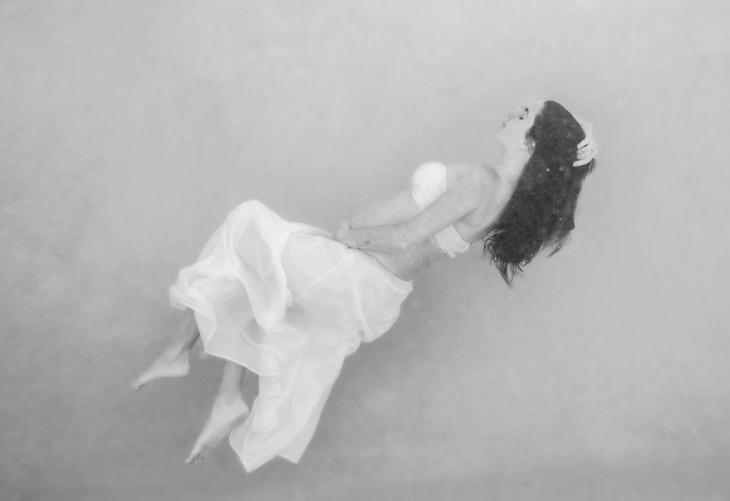White fabric flowing gracefully against a light gray background in an artistic sequence.