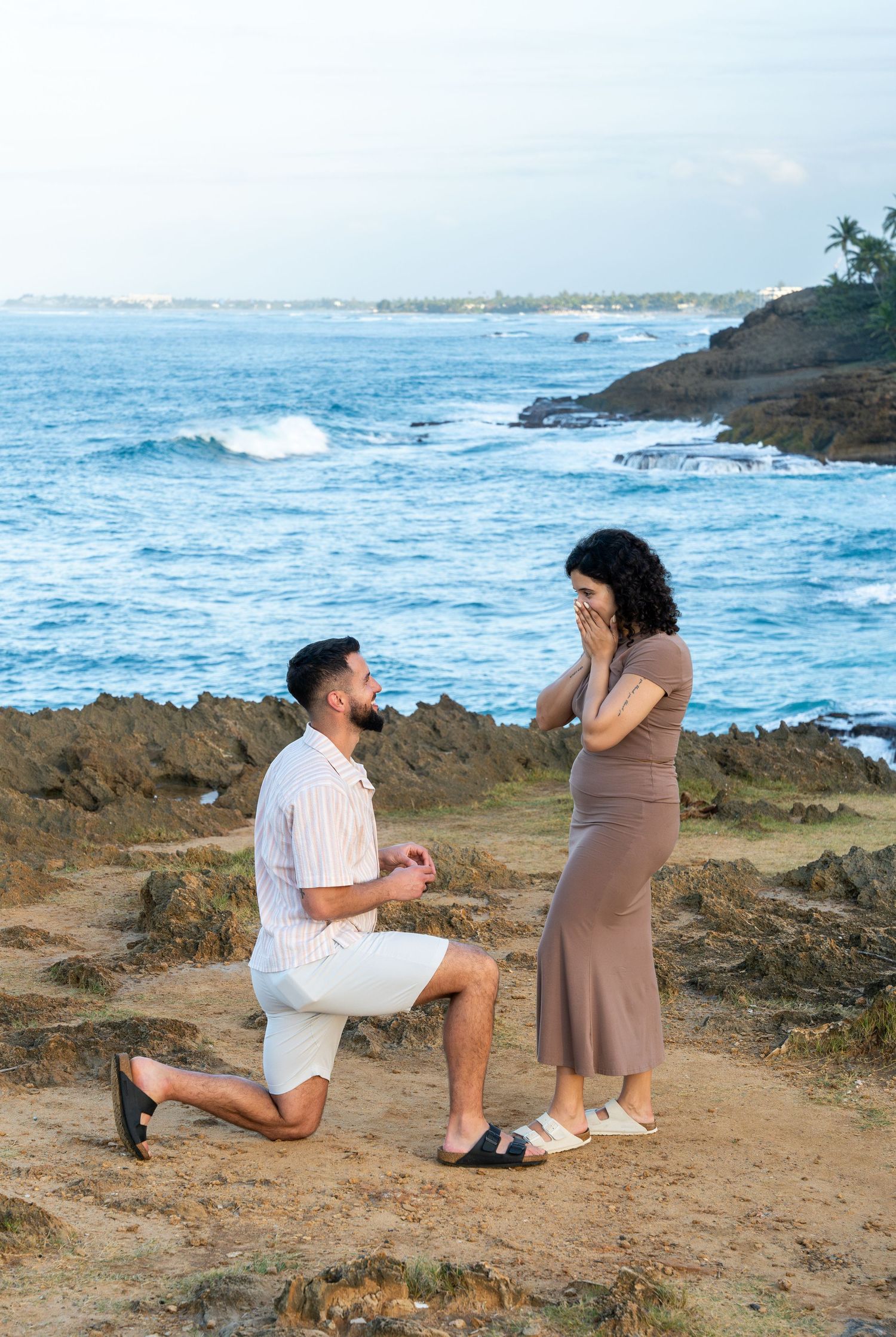 A romantic seaside proposal on rocky coastal cliffs, crashing waves in the background. Surprise proposal photoshoot in Puerto Rico