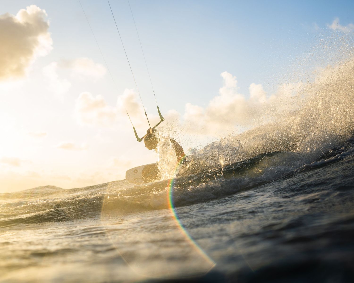Silhouetted kitesurfer catching waves during a golden sunset.