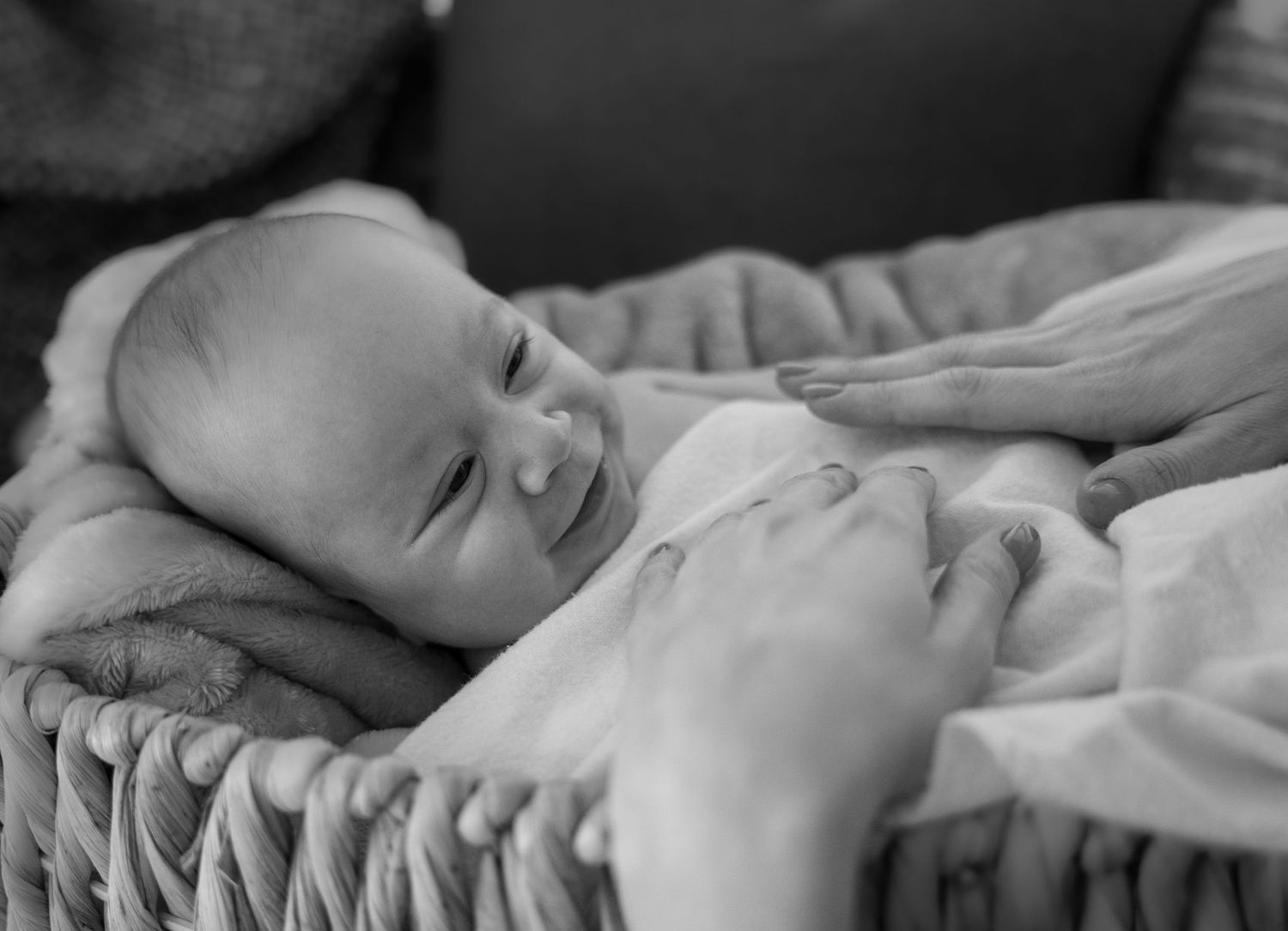 A sleeping newborn baby wrapped in white blankets rests peacefully on a soft surface.