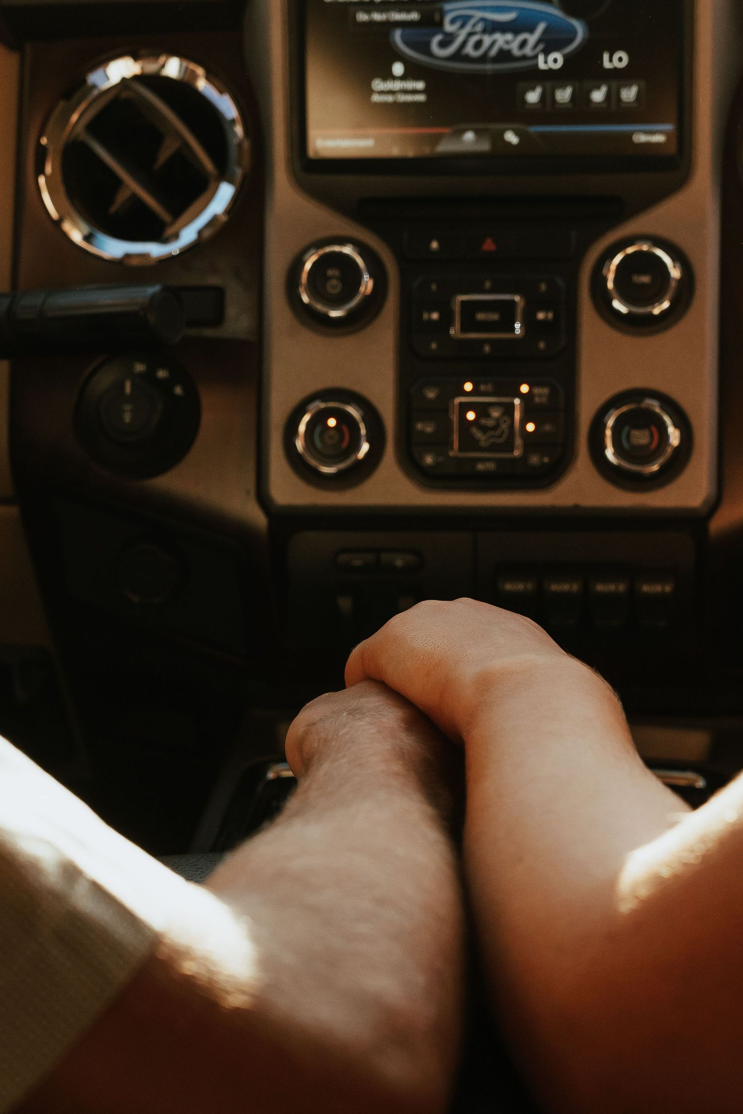 Two people holding hands inside a Ford truck, with the dashboard and infotainment screen visible in the background.