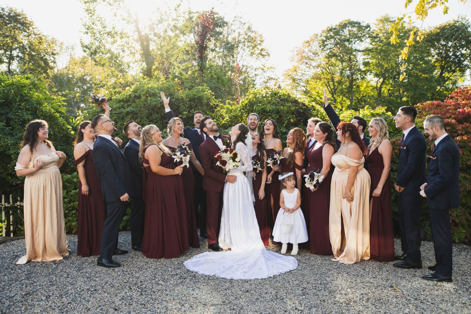 Wedding party poses together in formal attire at an outdoor venue during autumn season.