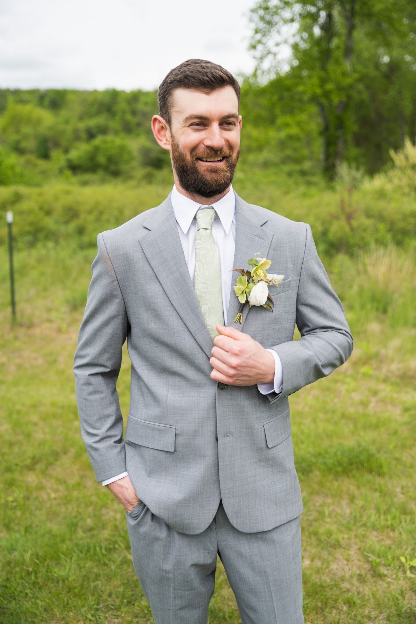 Wedding attire features light gray suit with pale yellow tie and floral boutonniere.