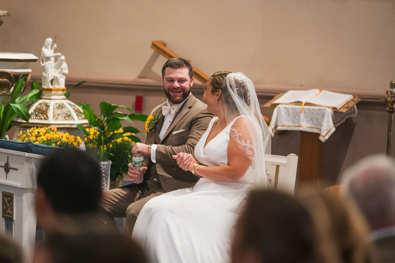 Wedding ceremony taking place in a traditional church setting with floral decorations.