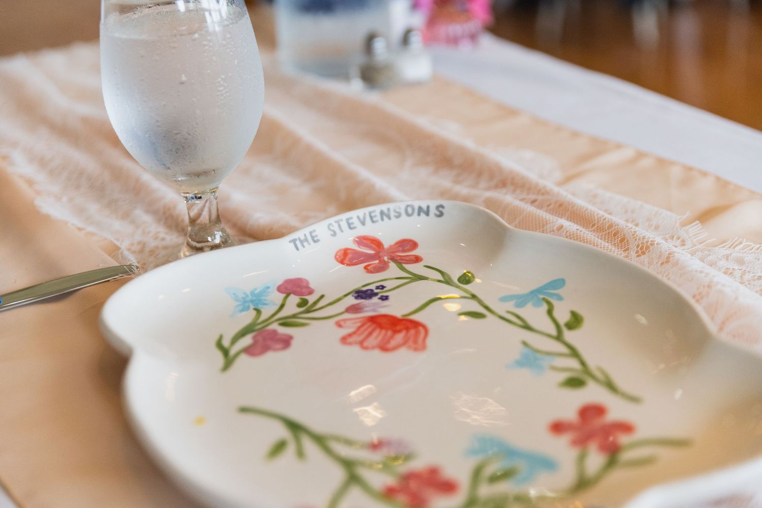 Elegant wedding table settings with floral decorated plates and soft peach tablecloths.