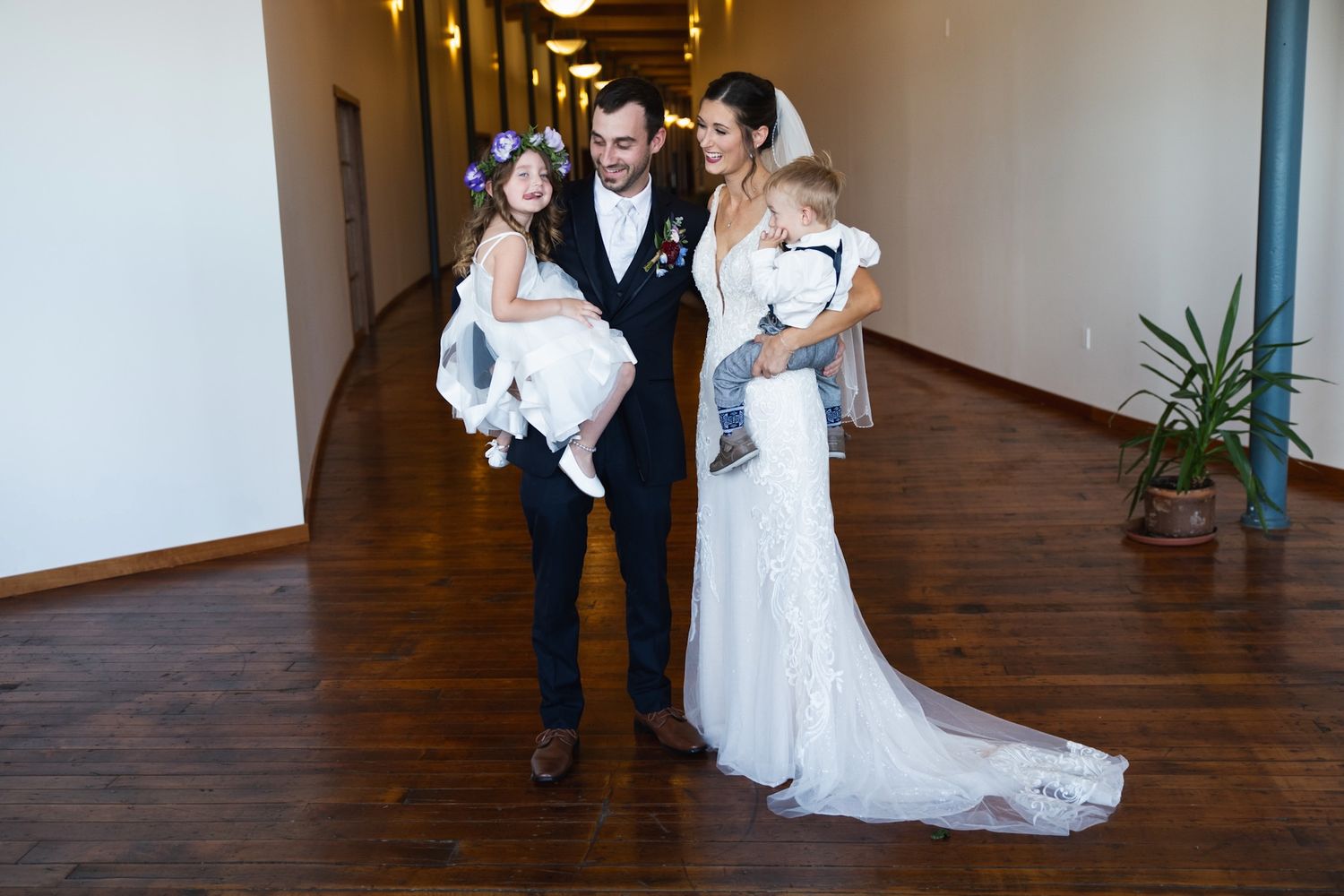 A wedding party posing in an elegant hallway with wooden floors.