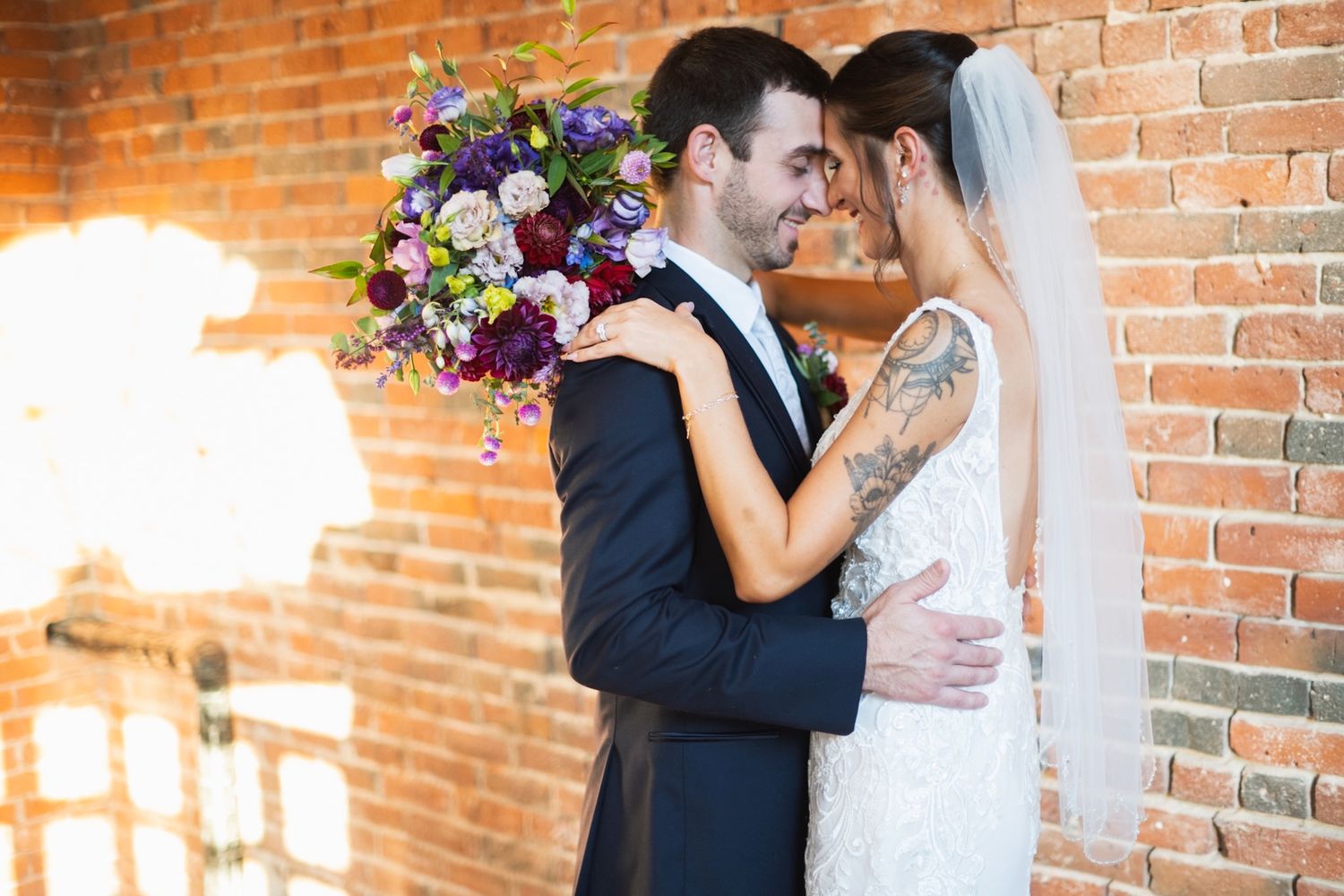 Rustic brick wall wedding venue provides warm backdrop for romantic couple portraits.