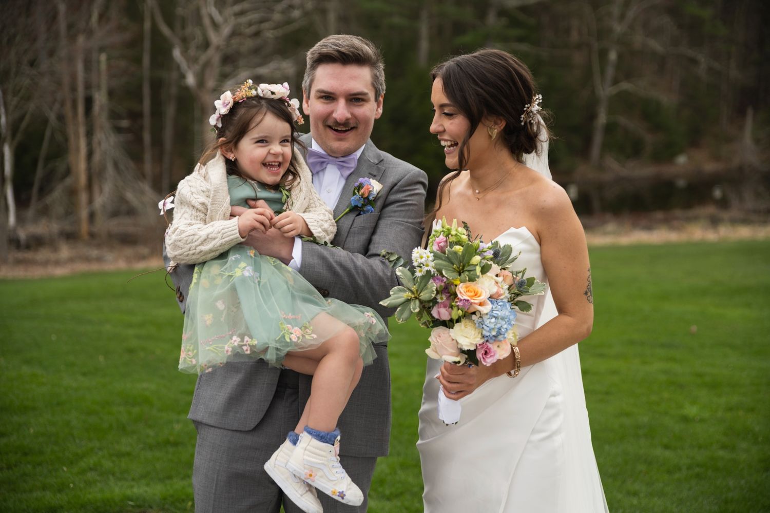 Joyful wedding portrait on green lawn with mint dress detail.
