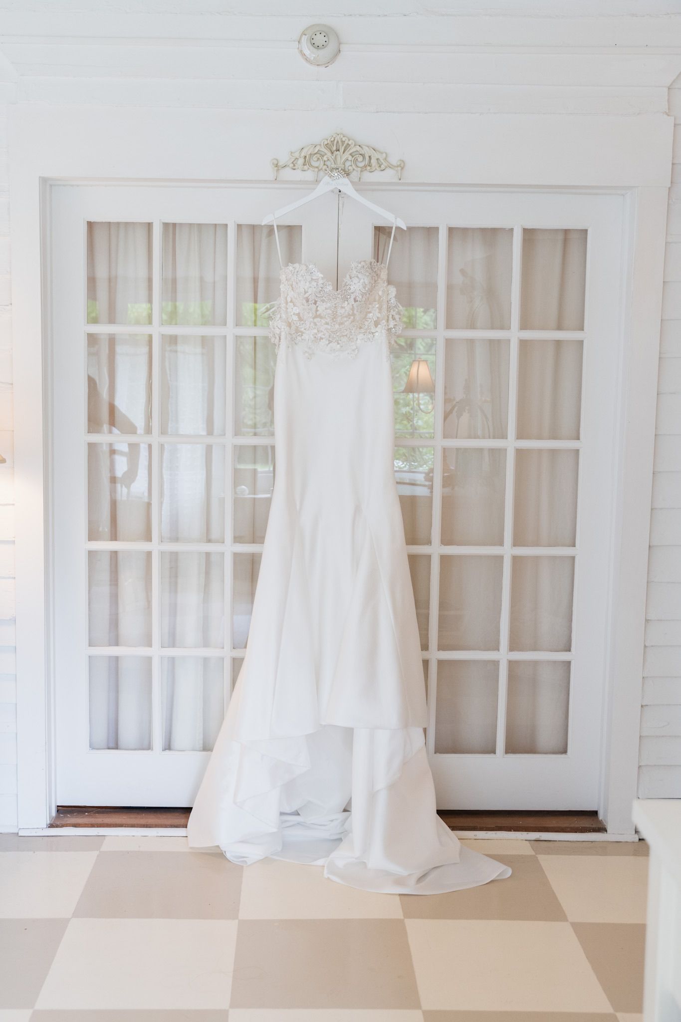 White wedding gowns displayed in an elegant bridal boutique with french doors.