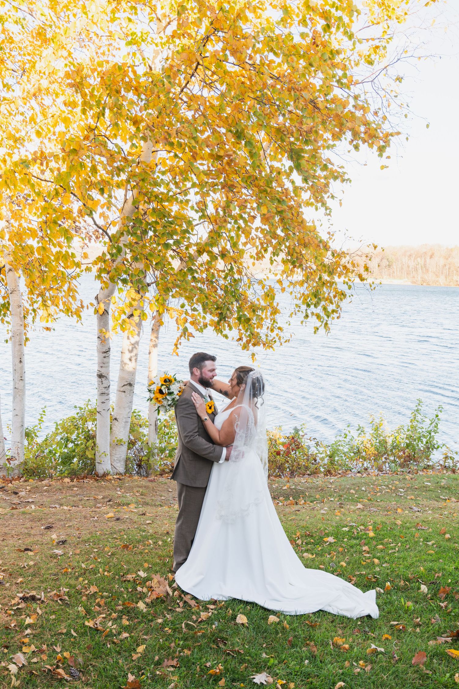 A romantic autumn photoshoot by a lake with golden birch trees in the background.