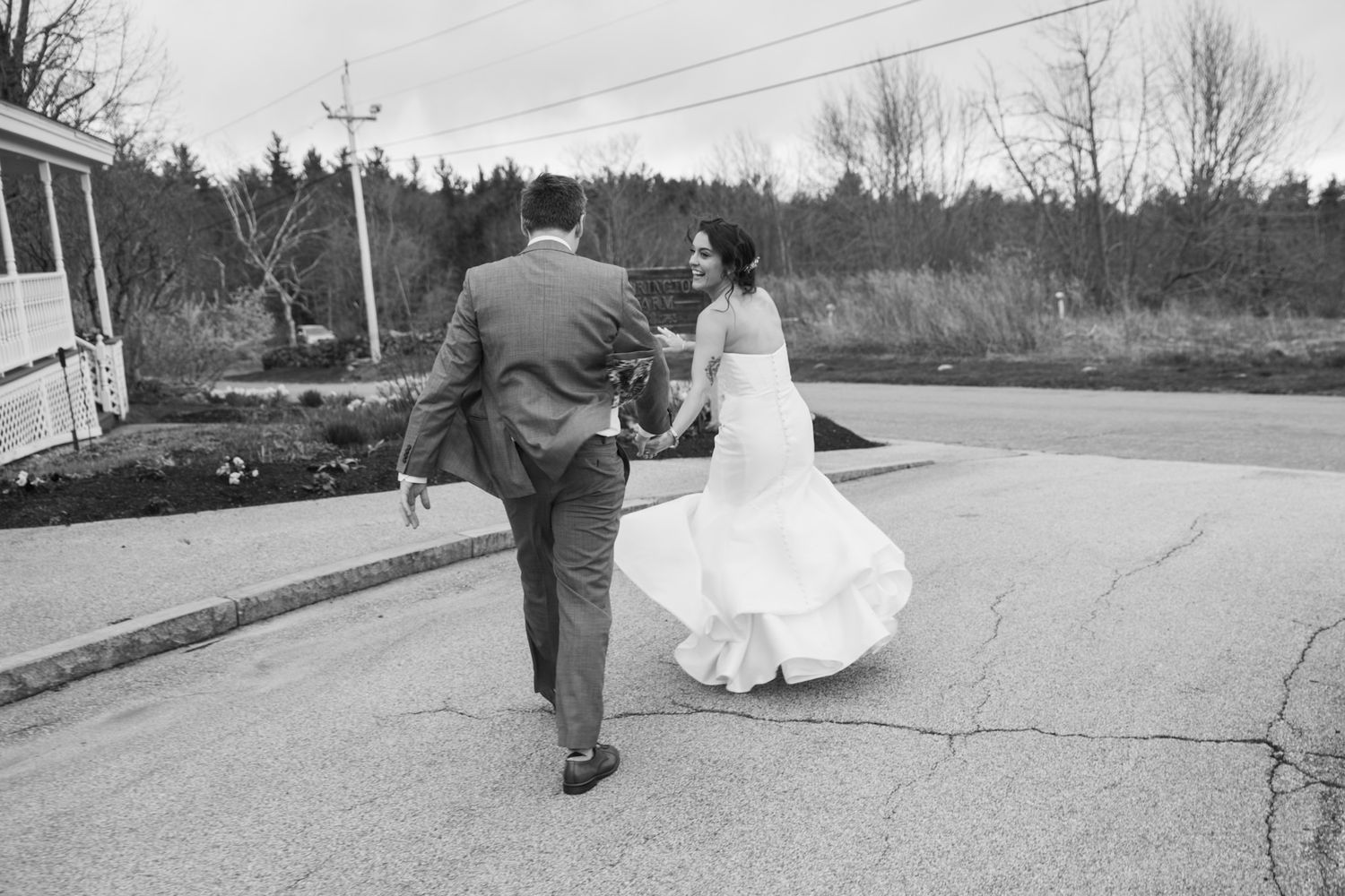 Black and white photo of couple walking together outdoors in wedding attire.