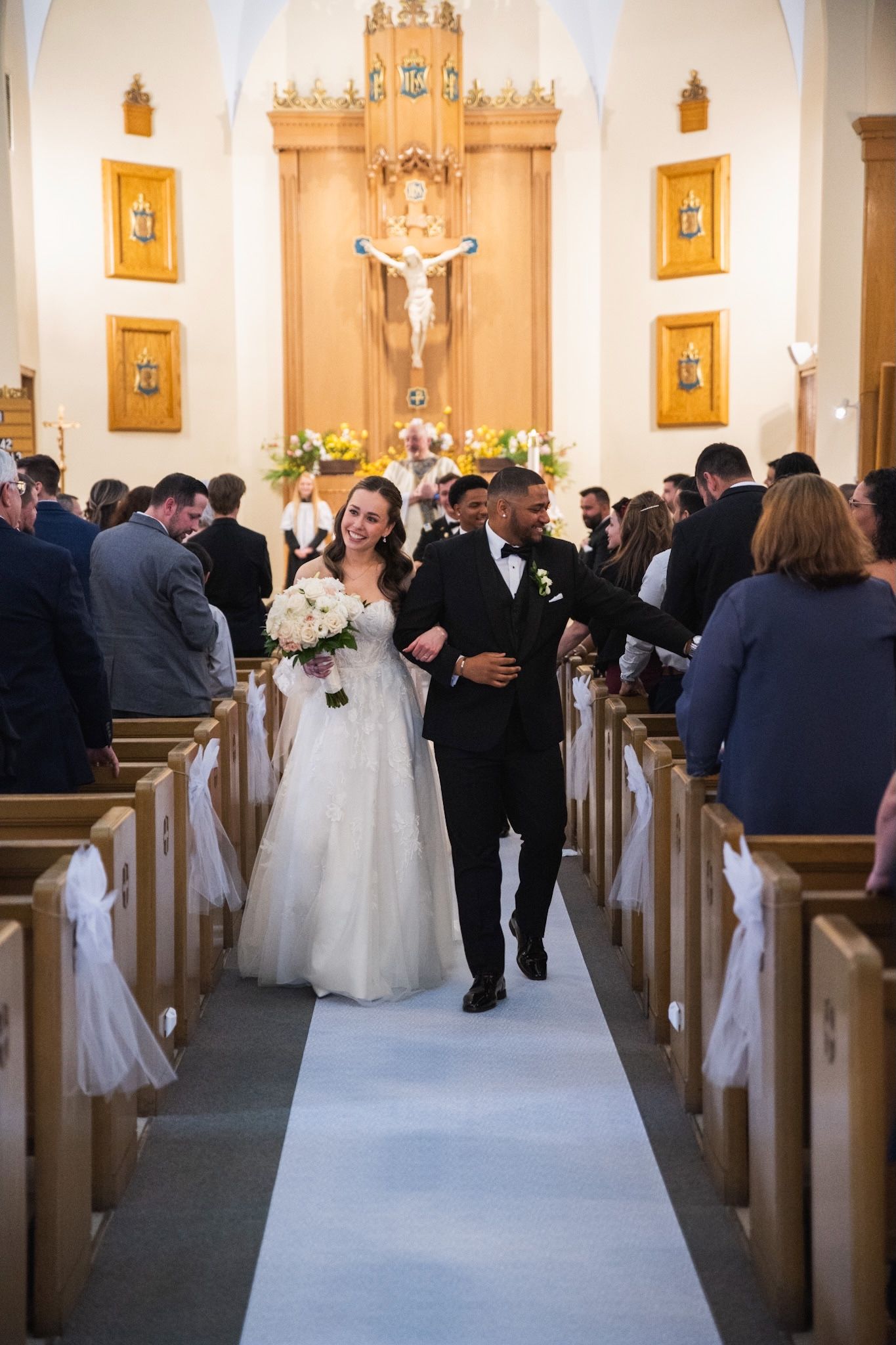 Traditional church wedding ceremony with white aisle runner and floral decorations.