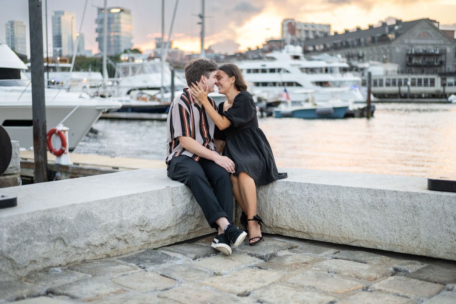 A waterfront engagement photo series at sunset with boats and city views in the background.