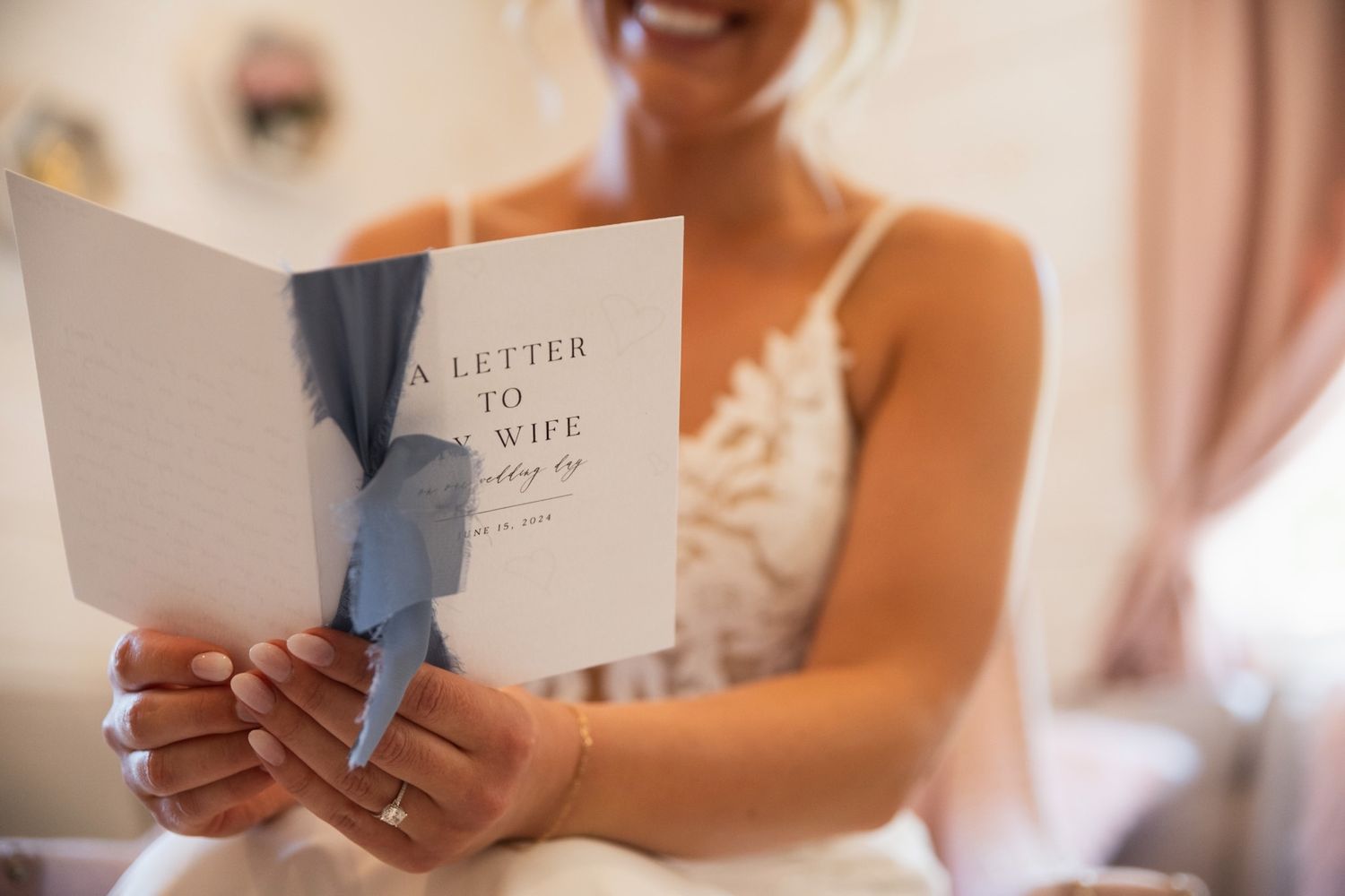 Wedding detail flatlay showing elegant white invitations, flowers and accessories on a light background.