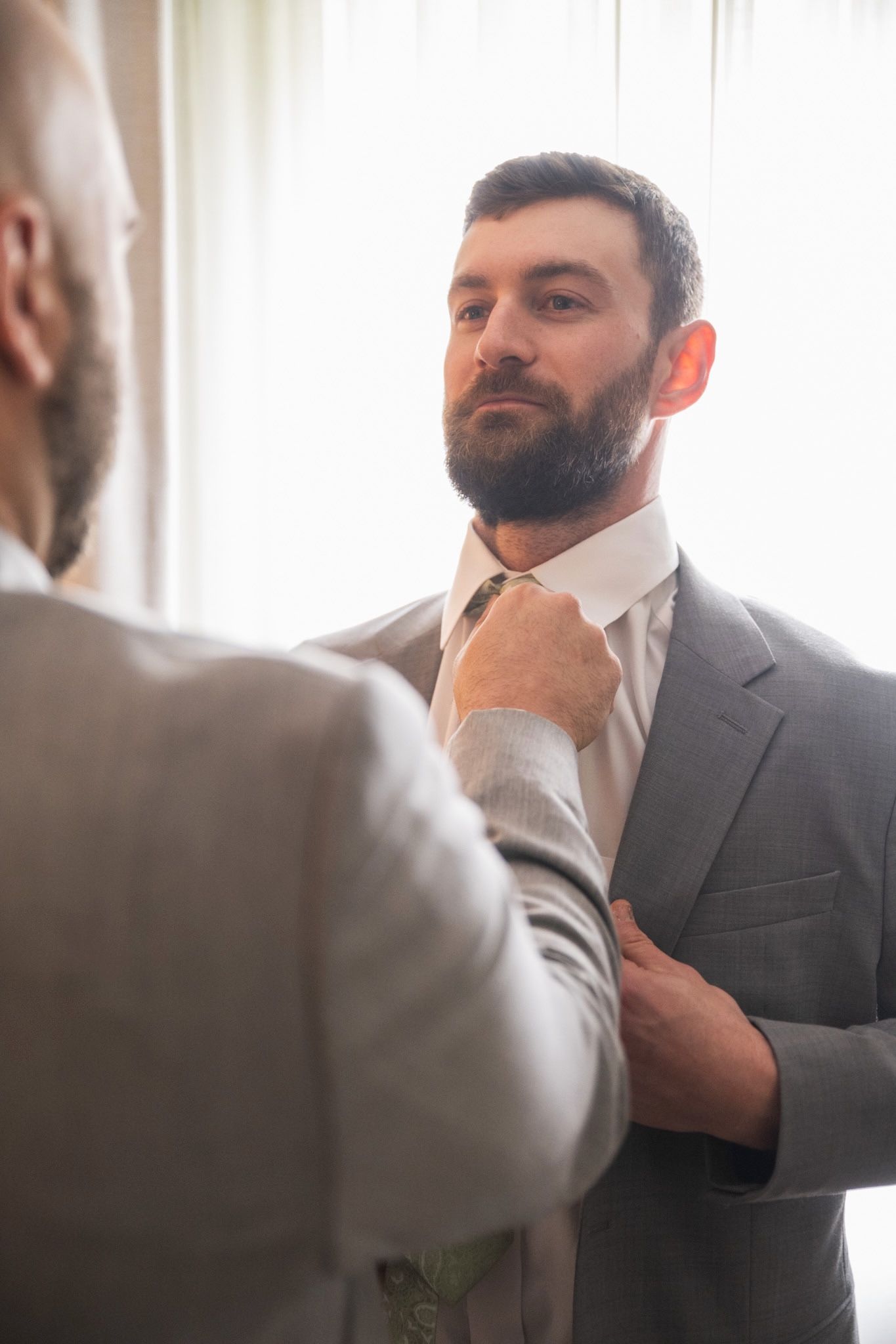 Man adjusting formal suit and tie while getting ready.
