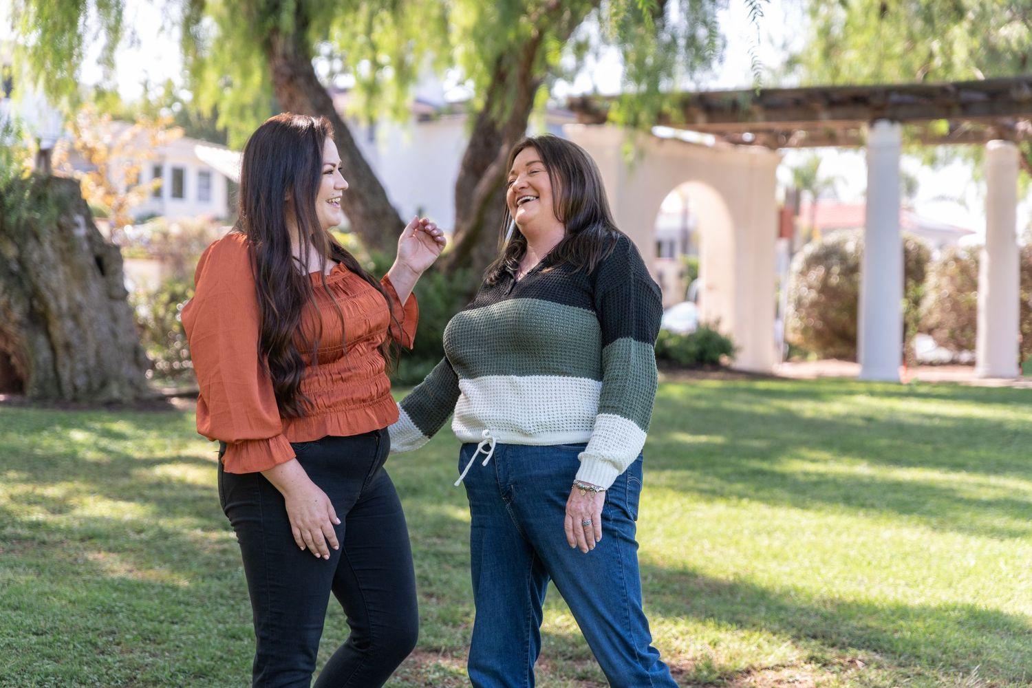 Family members stand together in a grassy outdoor setting on a sunny day.