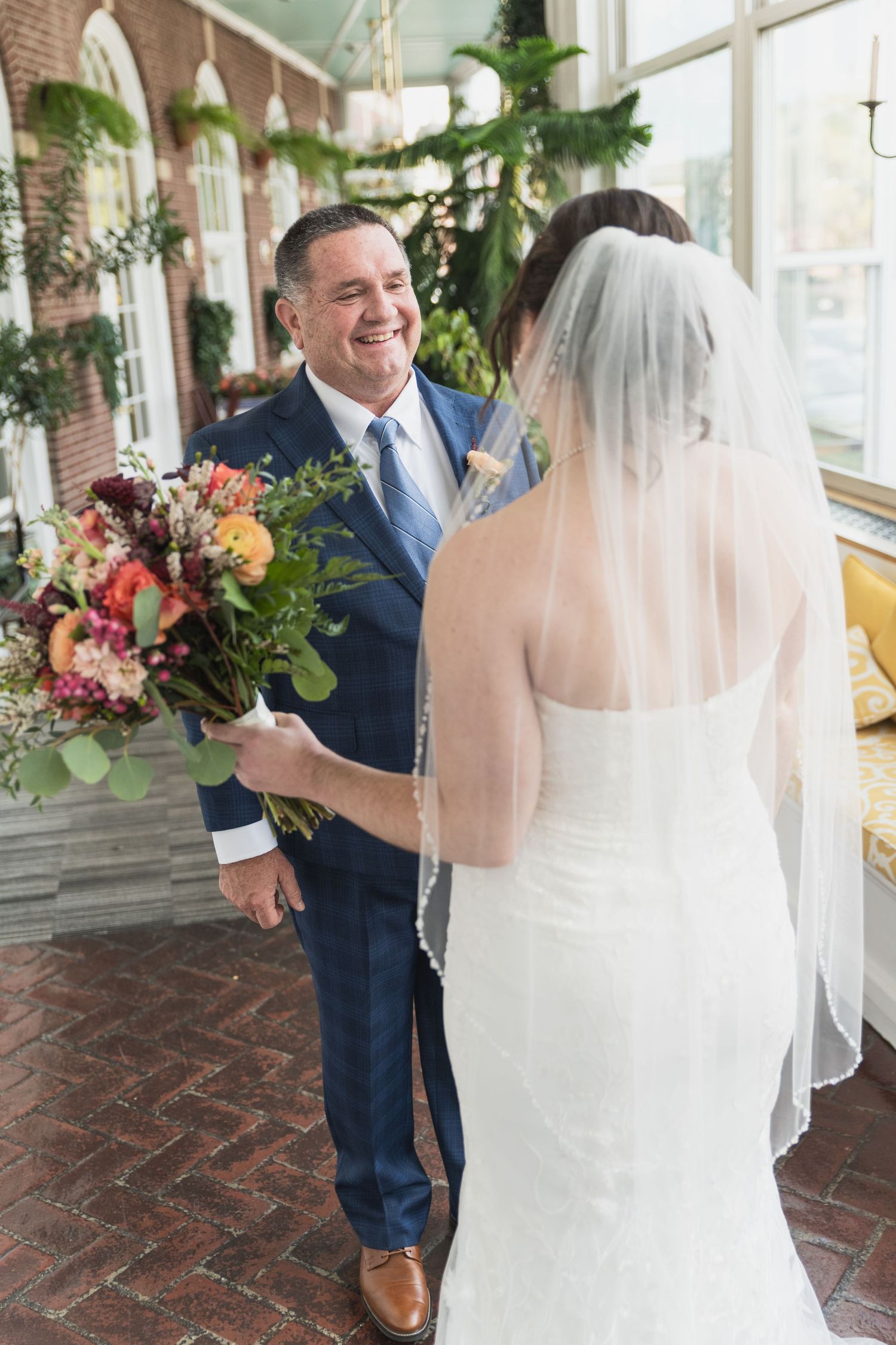 A series of first look wedding photos showing a bride in white dress and groom in navy suit meeting in a sunlit indoor space.